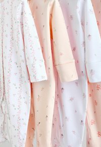 Fire babybodyer i forskellige pastelfarver: hvid med blomsterprint, lyserød med fe-illustrationer og blød ferskenfarvet.