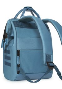 Zaino in tessuto blu con spallacci imbottiti, tasca frontale con zip e dettagli texture. Presenta molteplici scomparti di stoccaggio e un design strutturato.