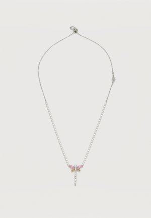 Collier en chaîne argentée avec un pendentif libellule ornée de pierres précieuses rose, bleue et ambre sur un fond blanc.