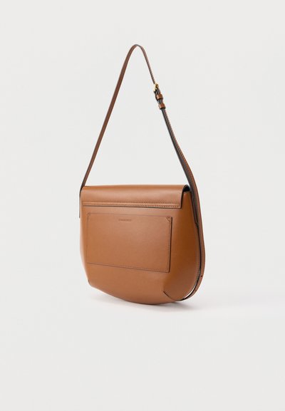 Καφέ δερμάτινη τσάντα ώμου με μπροστινή τσέπη και ρυθμιζόμενο λουράκι, τοποθετημένη πάνω σε λευκό φόντο.