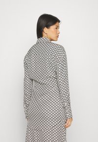 Long-sleeve dress featuring a black and white scallop pattern with a high collar, tailored fit, and smooth fabric texture.