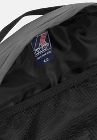 L'interno della borsa K-Way grigia mostra una fodera nera con un'etichetta del marchio visibile, con il testo "ONLY ONE SIZE" e il numero "4.0" stampato.