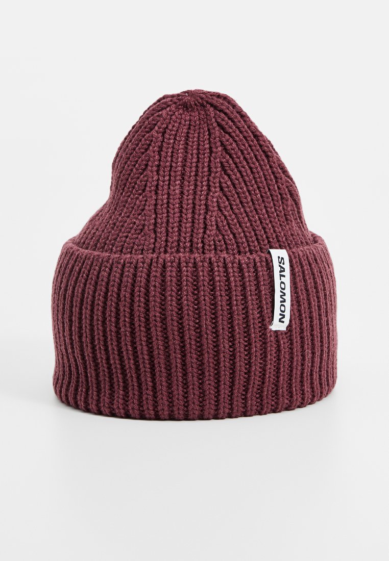 Gorro de punto burdeos con textura acanalada, que presenta un puño doblado y una etiqueta de marca blanca en el lado.