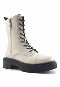 Bota alta con cordones en faux cuero beige claro y suela de goma negra. Cuenta con una cremallera lateral y cordones negros para un ajuste seguro.