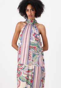 Top senza maniche con scollo halter in tessuto leggero, caratterizzato da intricati motivi floreali e righe nei colori rosa, verde e blu su uno sfondo crema.