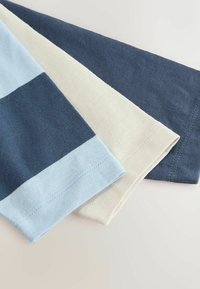 Tre foldede T-shirt ærmer i marineblå, cremefarvet og lyseblå med marineblå striber på en lys overflade.