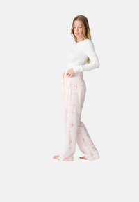 Maglietta bianca a maniche lunghe abbinata a pantaloni da pigiama a righe pastello con un motivo di occhiali e labbra. Tessuto morbido e leggero.