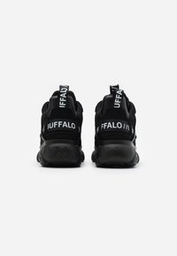 Une paire de baskets Buffalo noires vues de l'arrière, avec des tirettes blanches audacieuses portant la marque "BUFFALO" et des semelles épaisses.