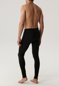 Czarne legginsy wykonane z gładkiego, elastycznego materiału, z dopasowanym krojem, wygodnym paskiem w talii i mankietami u dołu.