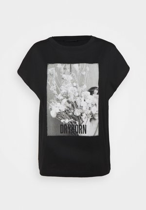 Czarna koszula z krótkim rękawem z monochromatycznym zdjęciem osoby trzymającej duży bukiet kwiatów, tekst "DRYKORN" pod obrazkiem.