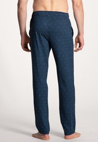Marineblauwe pyjamabroek met verticale strepen en kleine witte stippen. Elastische tailleband, relaxte pasvorm en lichte stof.