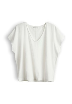 Blouse blanche à manches courtes, col en V et coupe ample, avec une petite étiquette de marque au niveau de l'encolure, présentée sur un fond blanc uni.