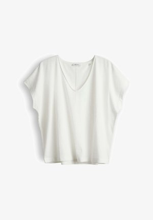 Blouse blanche à manches courtes, col en V et coupe ample, avec une petite étiquette de marque au niveau de l'encolure, présentée sur un fond blanc uni.