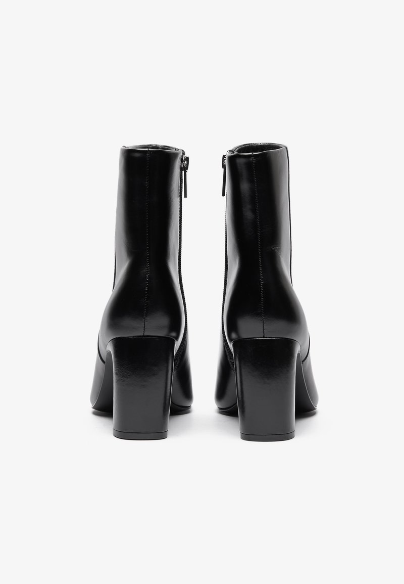 Czarne skórzane botki za kostkę o gładkim wykończeniu, kwadratowych obcasach i bocznych zamkach, prezentujące smukłą sylwetkę i minimalistyczny design.