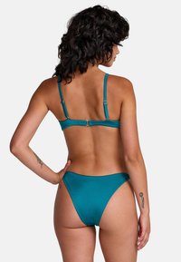 Conjunto de bikini azul verdoso con una textura elegante y suave, tirantes ajustables y cierre de broche en la parte trasera, con un diseño minimalista.