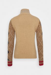 Pull tricoté beige avec un col haut, présentant des manches marron et bleues à motifs avec un accent rouge au poignet. Tissu texturé.