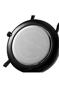 Černý kulatý pouzdro hodinek s nerezovou ocelí na zadní straně, s vyrytými detaily a korunkou na boku pro nastavení.