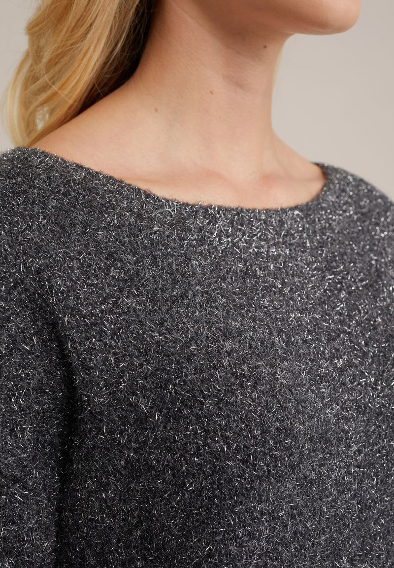 Pull en tricot gris avec un large décolleté, en tissu doux et texturé orné de paillettes argentées pour un détail supplémentaire.