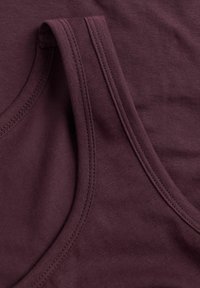 Burgundy tank top dengan tekstur halus, dilengkapi dengan tali lebar dan garis leher bulat, dihiasi dengan jahitan rapi di sepanjang tepinya.