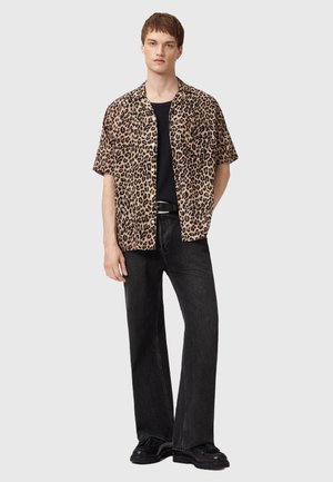 Short-sleeve leopard print shirt in brown and black, paired with black wide-leg jeans and black shoes, creating a casual look.