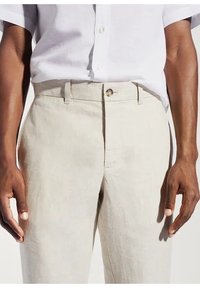 Pantaloni in lino beige con taglio dritto, dotati di zip frontale, due tasche anteriori e chiusura con un singolo bottone. Tessuto liscio.