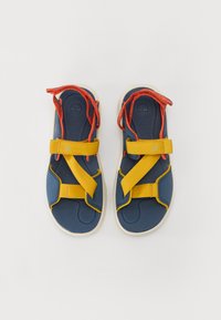 Sandal med marineblå materiale og gule og røde stropper. Justerbar stropdesign, teksturert fotseng og lys såle.