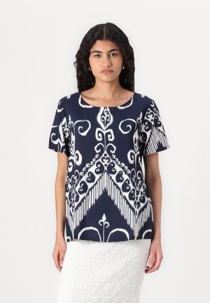 Navy short-sleeve top with white intricate pattern featuring scrolling designs and chevron accents. Soft fabric, relaxed fit, round neckline.