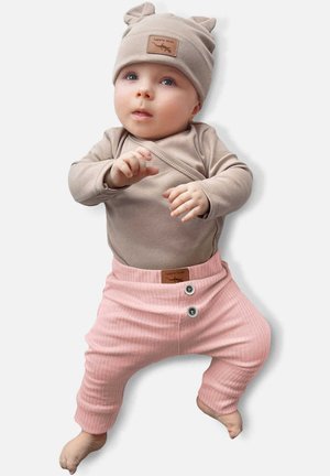 Beige lange mouw bodysuit, lichtroze ribbroek met twee knopen, en een bijpassende beige hoed met oren en een leren label.