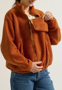 Orange, flauschige Fleecejacke mit hohem Kragen, Frontreißverschluss und einer quadratischen Tasche. Der elastische Saum und die gekröpften Ärmel schaffen eine entspannte Form.
