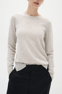 Light grey knitted sweater with long sleeves, round neckline, and subtle texture. Paired with black high-waisted trousers, featuring a flat front.