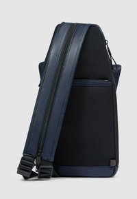 Borsa a tracolla blu navy con una combinazione di tessuto strutturato e pelle liscia. Include doppie cerniere, una tasca esterna e tracolla regolabile.