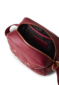 Borsa in pelle bordeaux con design trapuntato, chiusura con zip dorata e un interno nero testurizzato che presenta una piccola tasca inserita.