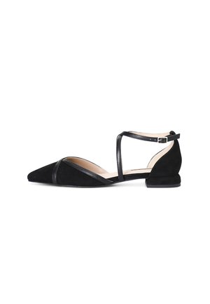 Scarpa piatta in suede nera con punta affusolata, cinturino alla caviglia e tacco basso; presenta dettagli in pelle e un design minimalista.