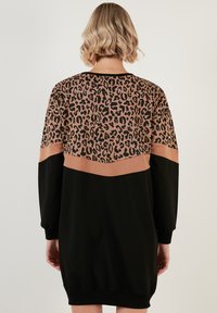 Schwarzes Strickkleid mit einem Oberteil im Leopardenmuster, beigem Akzentband und langen Ärmeln, das über einen lockeren Schnitt und eine weiche Textur verfügt.