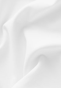 Vitt tyg draperat mjukt, som visar en jämn textur och subtil glans, med mjuka kurvor och veck över hela ytan.