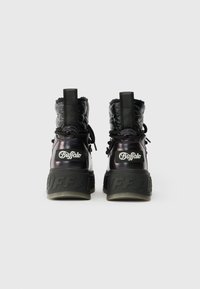 Melnas potītes zābaki ar spīdīgu apdari, ar mīksto augšdaļu, unikālām tekstūrām un izteiksmīgu gumijas zoli, kurā uz heel ir iespiests zīmola logo.