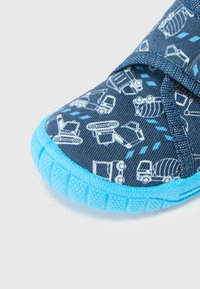 Blå småbarnsskor med ett mönstrat marinblått textil med ljusblåa byggfordon och en texturerad gummisula. Design med justerbar rem.