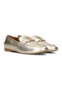 Gouden metallic loafers met een gladde textuur, ronde neus en dubbele band met gouden hardware accenten. Platte zool en lichtbruine binnenkant.