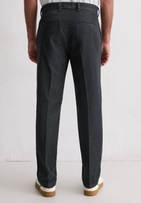 Ciemnoszare spodnie o dopasowanym kroju, z dwoma tylnymi kieszeniami i delikatnymi zakładkami. Wykonane z gładkiego materiału, z klasycznym paskiem w talii.