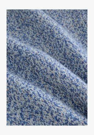 Paviršius su tekstūra įvairių mėlynos spalvos atspalvių, su pynimo raštu, kurį sudaro šviesiai ir tamsiai mėlyni siūlai, kuriantys minkštą ir jaukią išvaizdą.