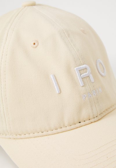 Beige cotton baseball cap with embroidered "IRO PARIS" in white, features a stitched brim and a top button. Minimalistic design.