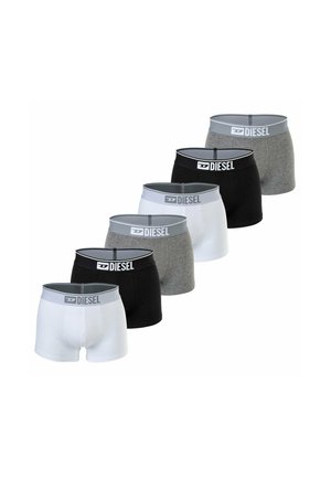 Oberkörperfreier Mann trägt schwarze Diesel-Boxershorts mit Logobund und steht vor einem schlichten hellen Hintergrund.