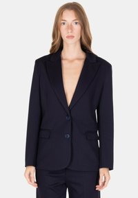 Blazer blu marino a righe sottili con revers a punta, chiusura monopetto con un bottone, due tasche anteriori e vestibilità strutturata. Tessuto liscio con una leggera lucentezza.