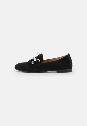 Mocassin en daim noir avec détail de boucle argentée et semelle plate, présenté en vue latérale sur fond blanc.