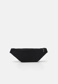 Svart minimalistisk midjeväska med dragkedjestängning och justerbar rem, visad mot en enkel vit bakgrund.