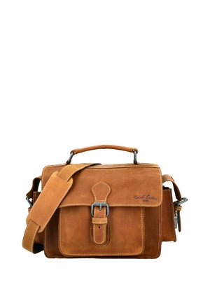 Ruda odinė kuprinė su priekiniu sagtimi, viršutine rankena, paminkštintu peties diržu ir šoninėmis kišenėmis ant balto fono.