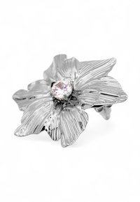 Anello d'argento a forma di fiore con petali texturizzati e una gemma centrale trasparente, caratterizzato da dettagliate trame fogliari e una finitura lucida.