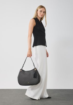 Sac en cuir noir texturé avec une forme courbée, des détails en or et un accent à frange. Porté avec une bandoulière, présentant un subtil motif géométrique.