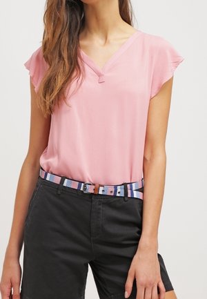 Jasnoróżowa bluzka z dekoltem w serek i krótkimi falbanianymi rękawami, zestawiona z czarnymi szortami i wielokolorowym paskiem w paski.