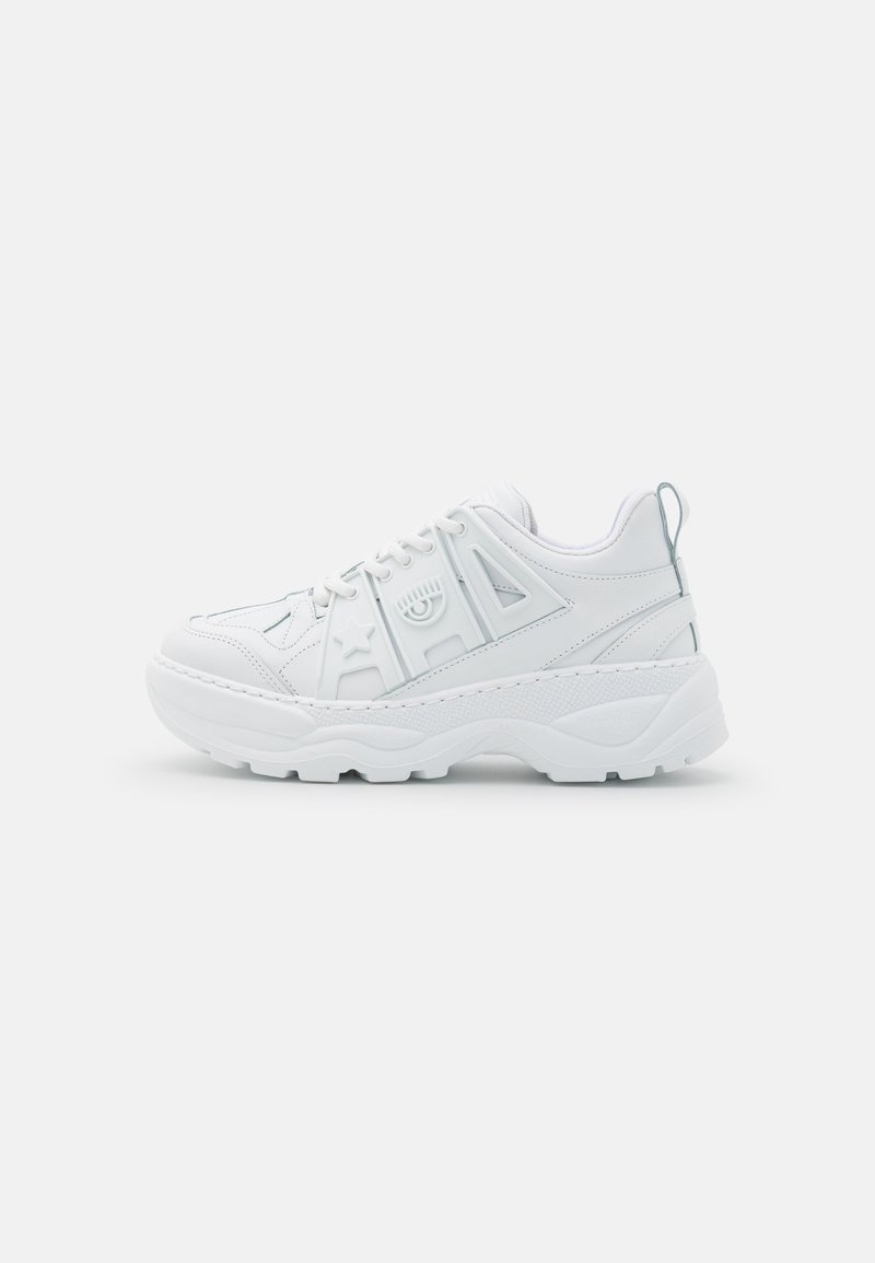Białe sneakersy z masywną podeszwą, wykonane z teksturowanego materiału syntetycznego. Posiadają geometryczne wycięcia, sznurowane z przodu oraz odsłonięty uchwyt z tyłu.